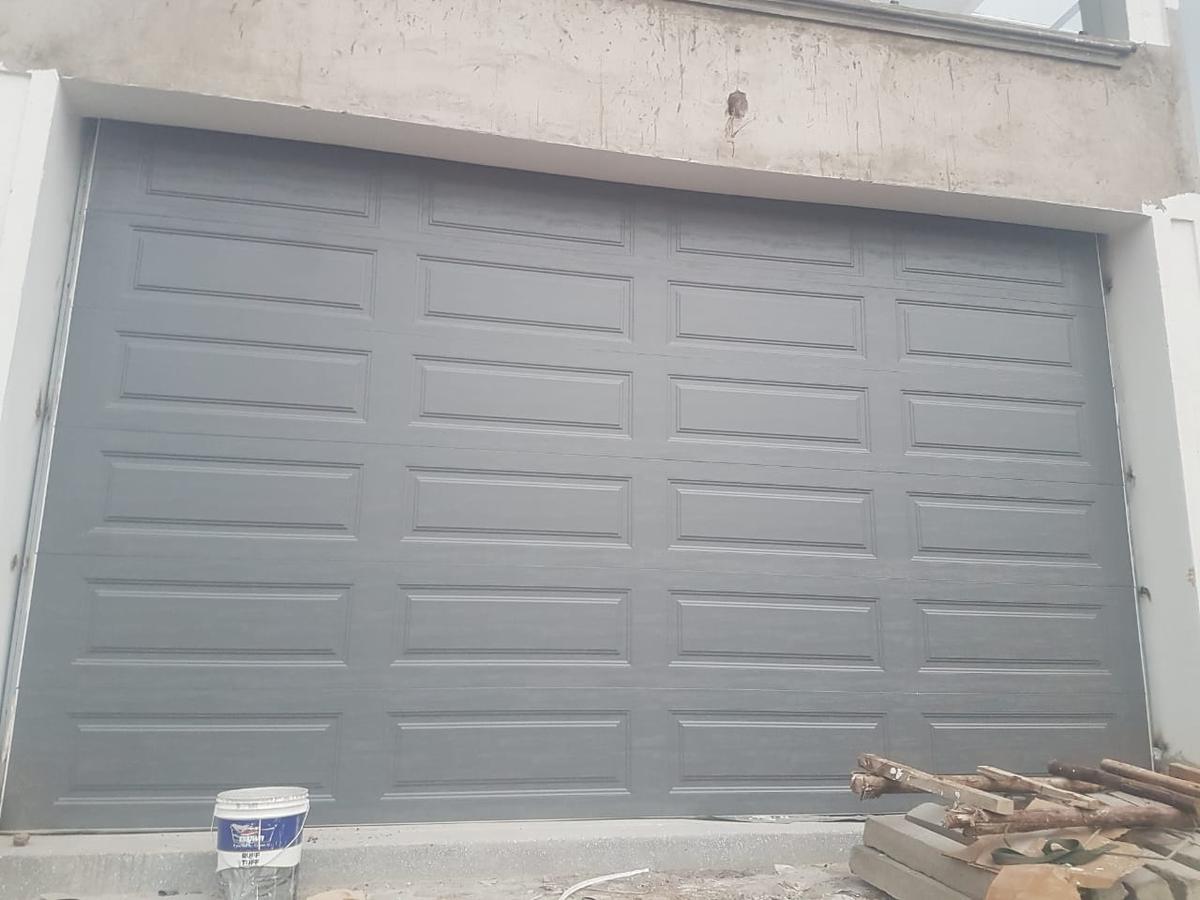 Grey raised-panel sectional garage door fitted in a new building opening