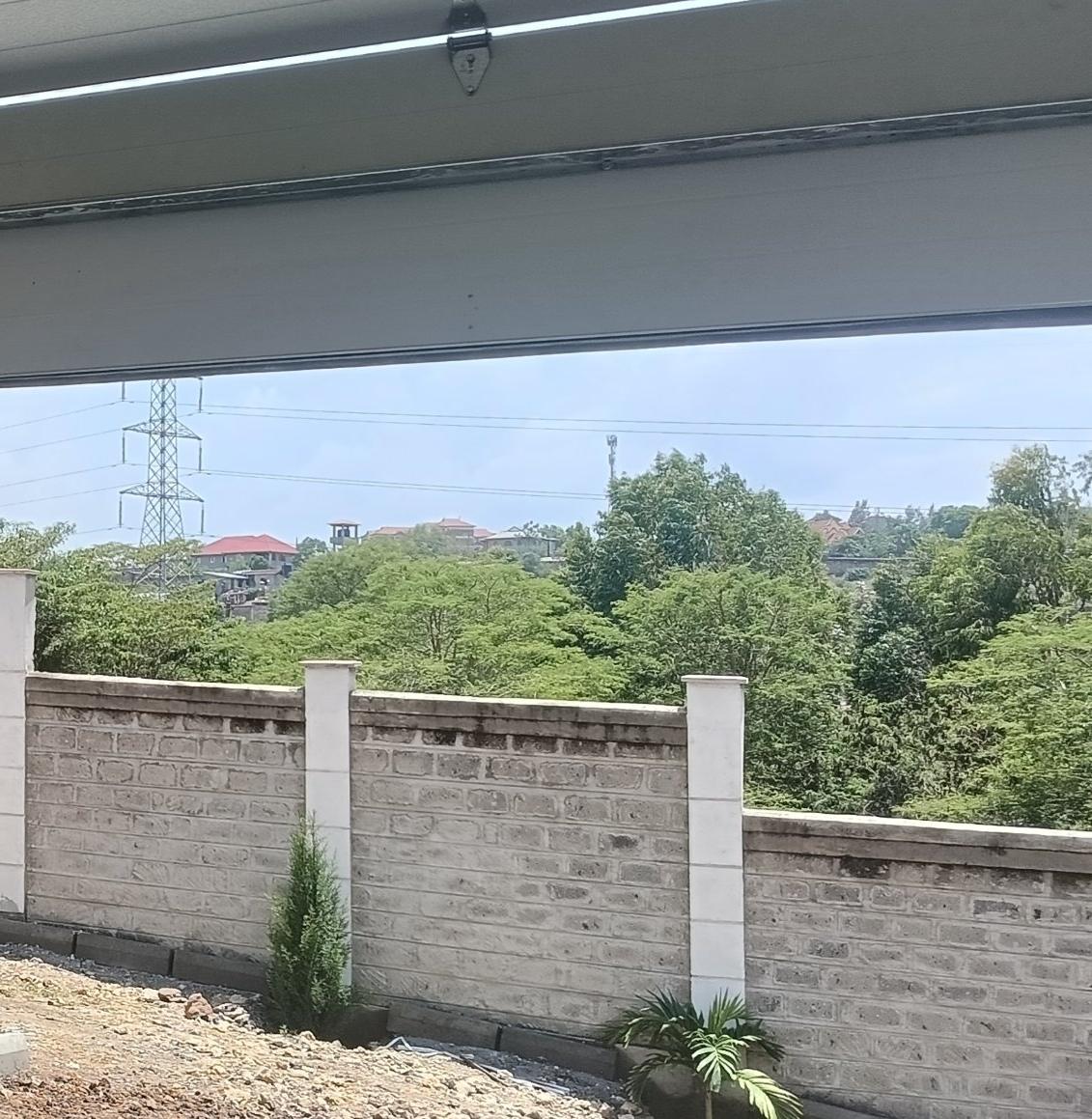 Insulated sectional garage door panels with hinges and track, partly open onto a compound wall
