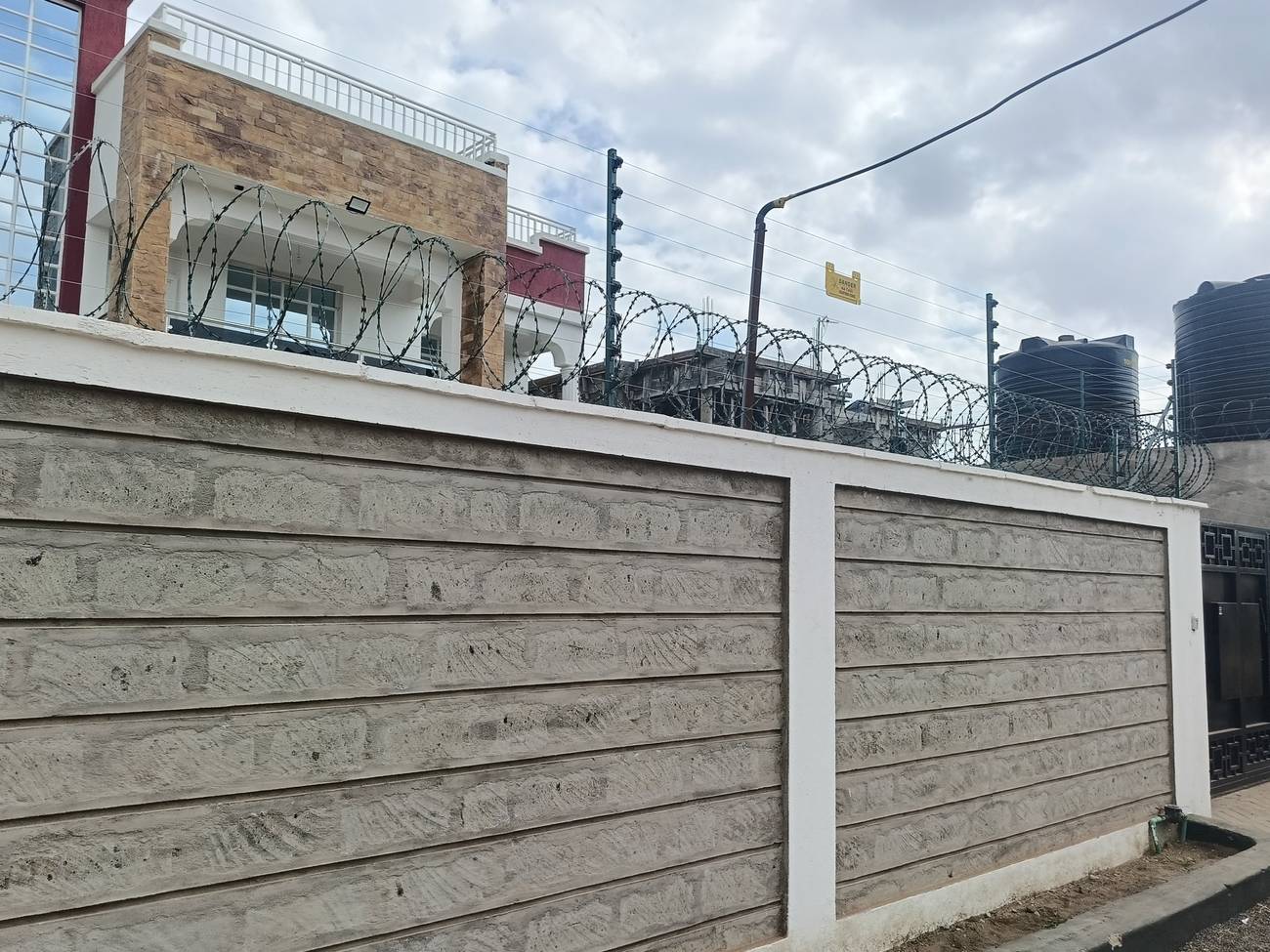 Electric fence and razor wire on top of a masonry perimeter wall